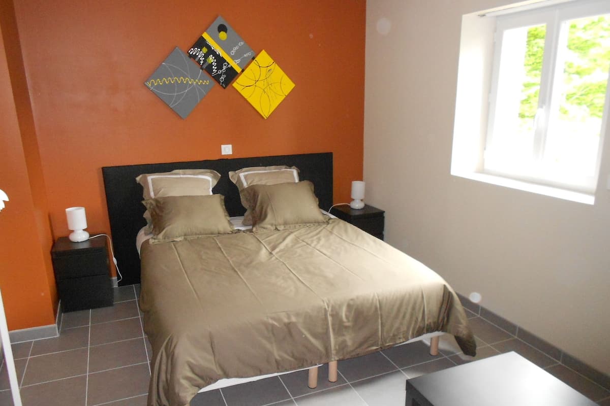 A bedroom with a bed, two bedside tables, and a window.