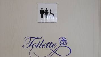 Señal de baño con el símbolo de accesibilidad para sillas de ruedas y la palabra 'Toilette' en una tipografía estilizada.