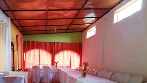 A long banquet table set up in a room with a tiled floor and a high ceiling. - Hotel Villa Los Arcos (Flores)