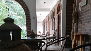 A dining area with wicker chairs, a table, and a hanging lantern. - Hotel Villa Los Arcos (Flores)