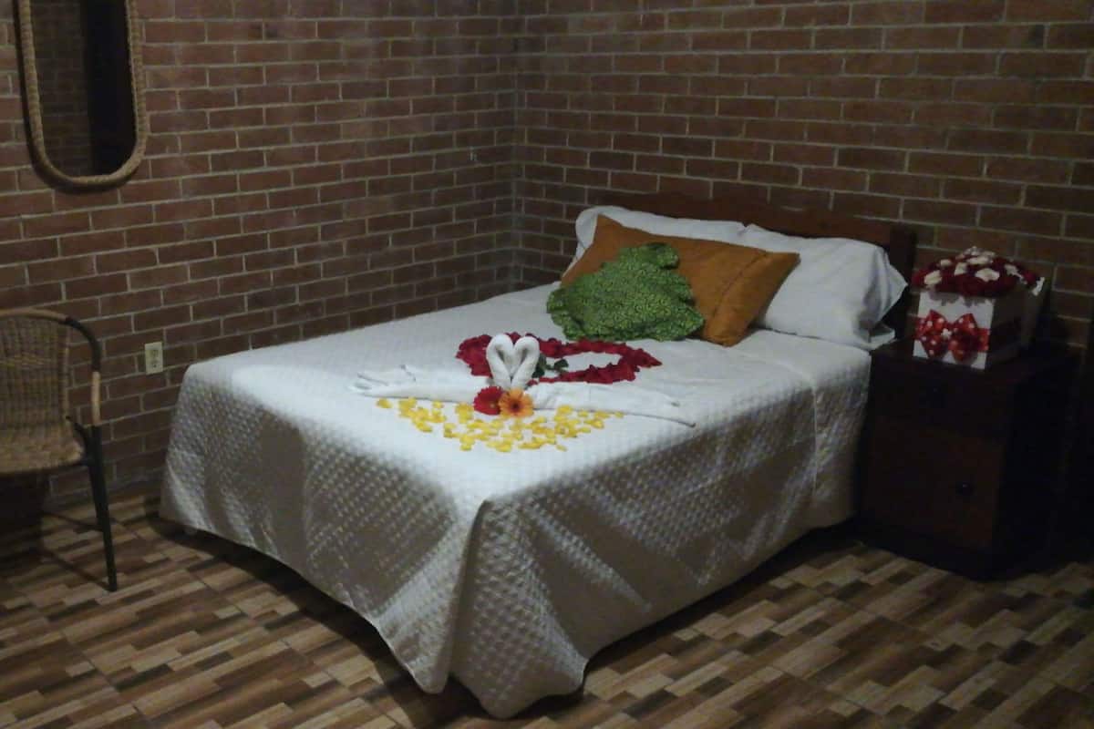 A neatly arranged bedroom with a bed, a chair, and a small table with a vase of flowers.