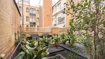 A courtyard with potted plants, outdoor seating, and a staircase leading to an upper level.