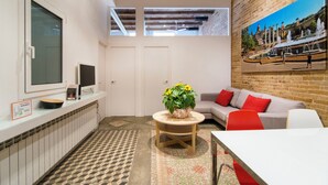 A compact living space with a kitchen area, a dining table, a sofa, and a painting on the wall. - Happy People Plaza España (Barcelona)