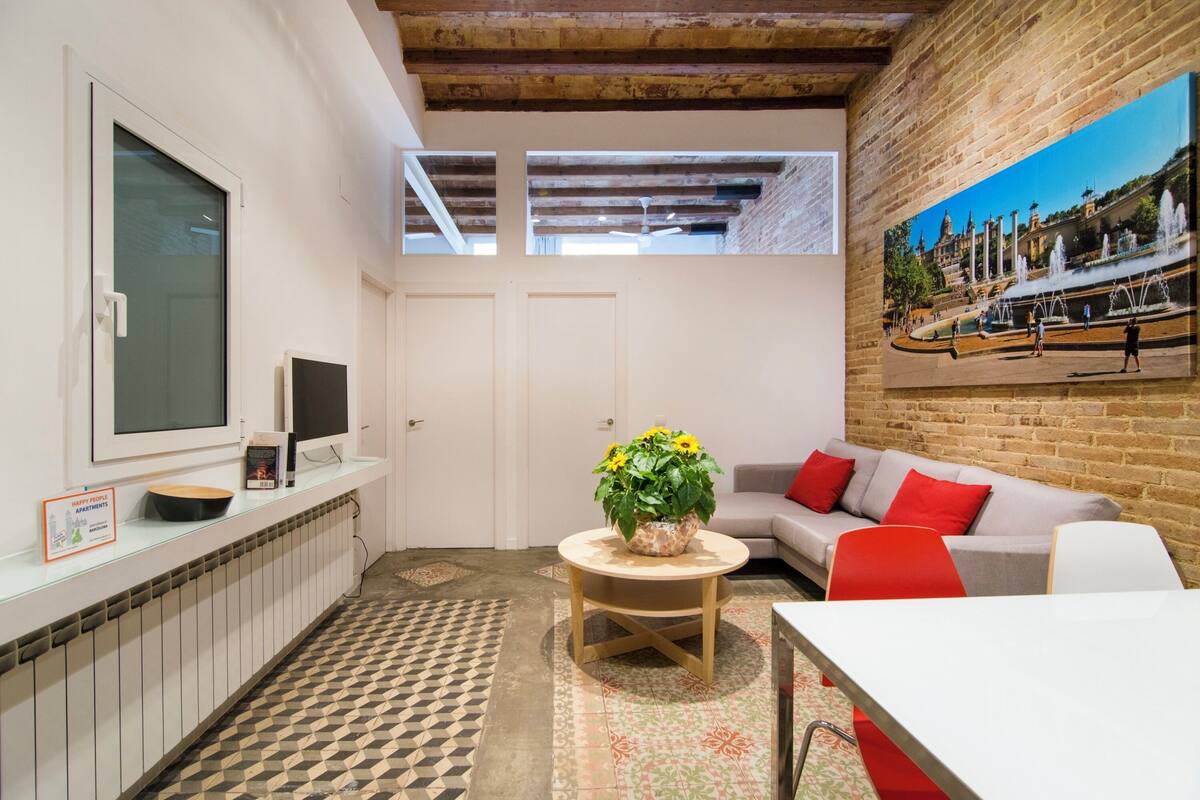 Um espaço compacto com cozinha, mesa de jantar, sofá e um quadro na parede.