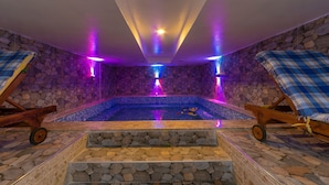 Ein Wellnessbereich mit Steinwand, kleinem Pool und zwei Liegestühlen.