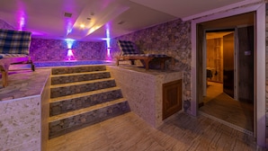 Ein Wellnessbereich mit Steinsäulen, einem Pool und einer Holztreppe.
