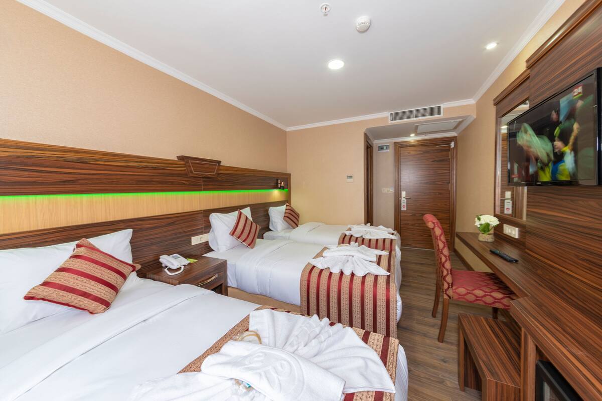 Une chambre d’hôtel avec deux lits, une télévision, un bureau et une chaise.