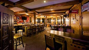 A cozy bar area with wooden beams, bar stools, and a counter. - Soda Butte Lodge (Cooke City)