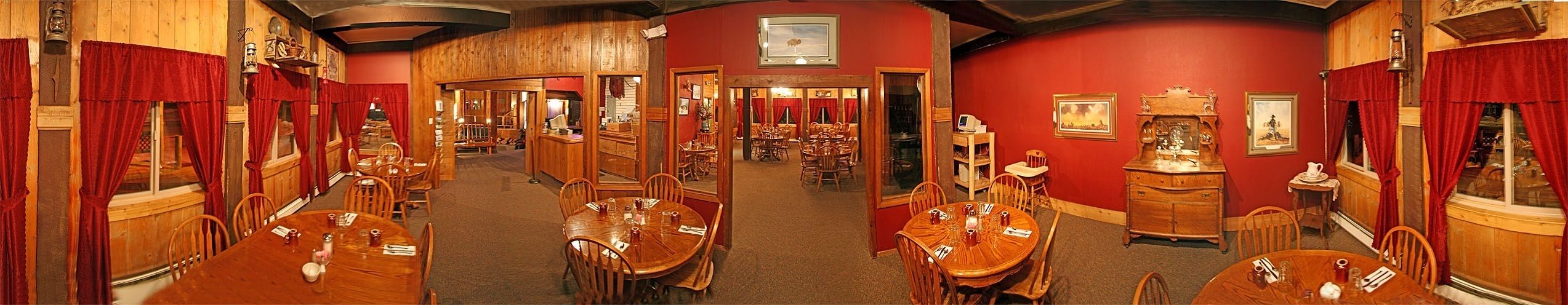 A hotel lobby with multiple dining areas, wooden furniture, and red walls.
