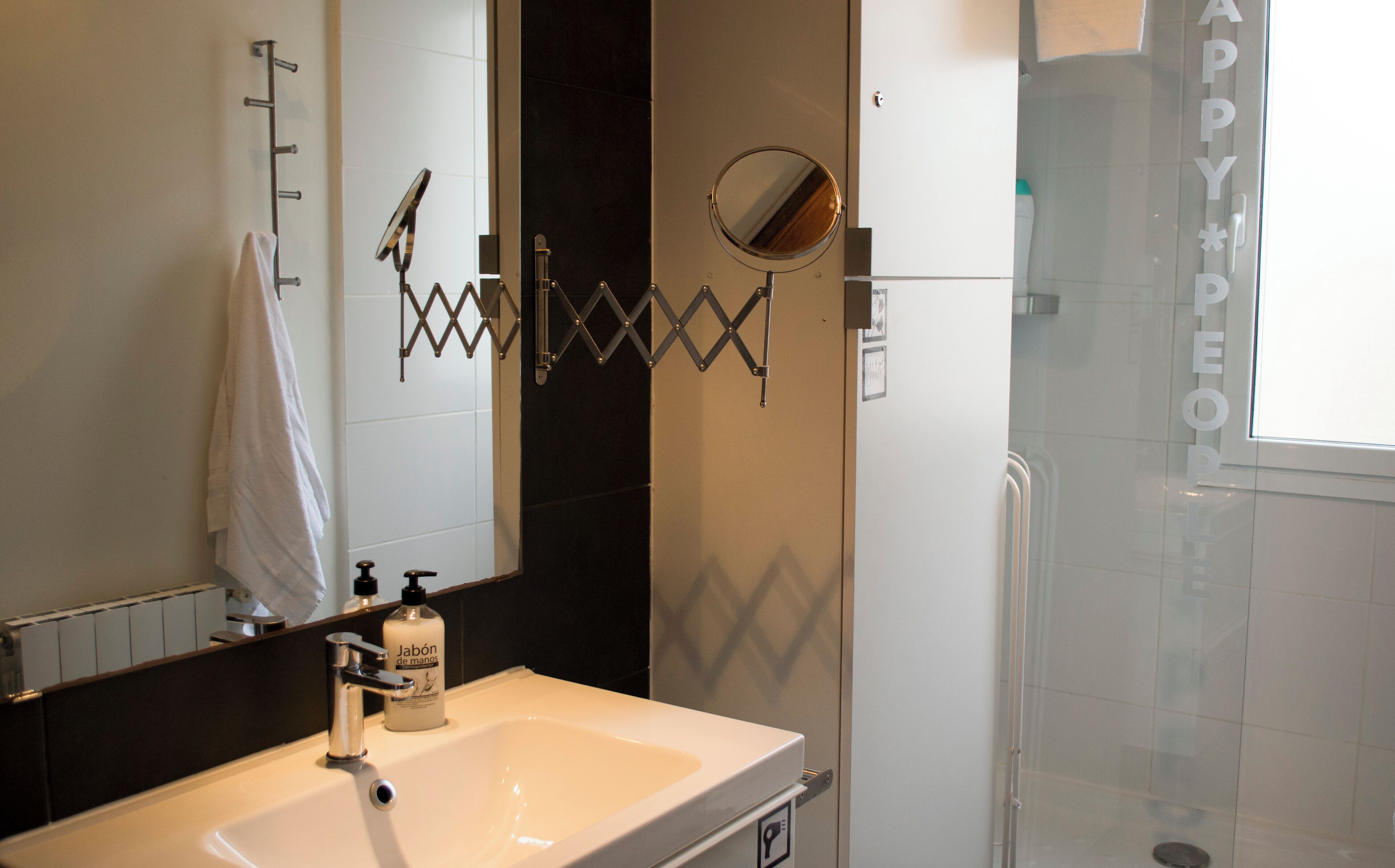A bathroom with a sink, mirror, towel rack, and a shower area.