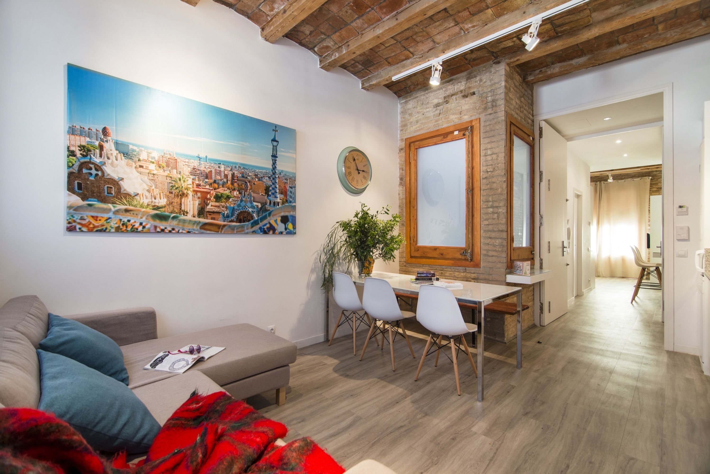 Un salon moderne avec un canapé, une table à manger et des chaises. Un grand tableau représentant un paysage urbain est accroché au mur.