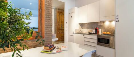 Una cocina moderna con armarios blancos, encimera de granito y horno empotrado.