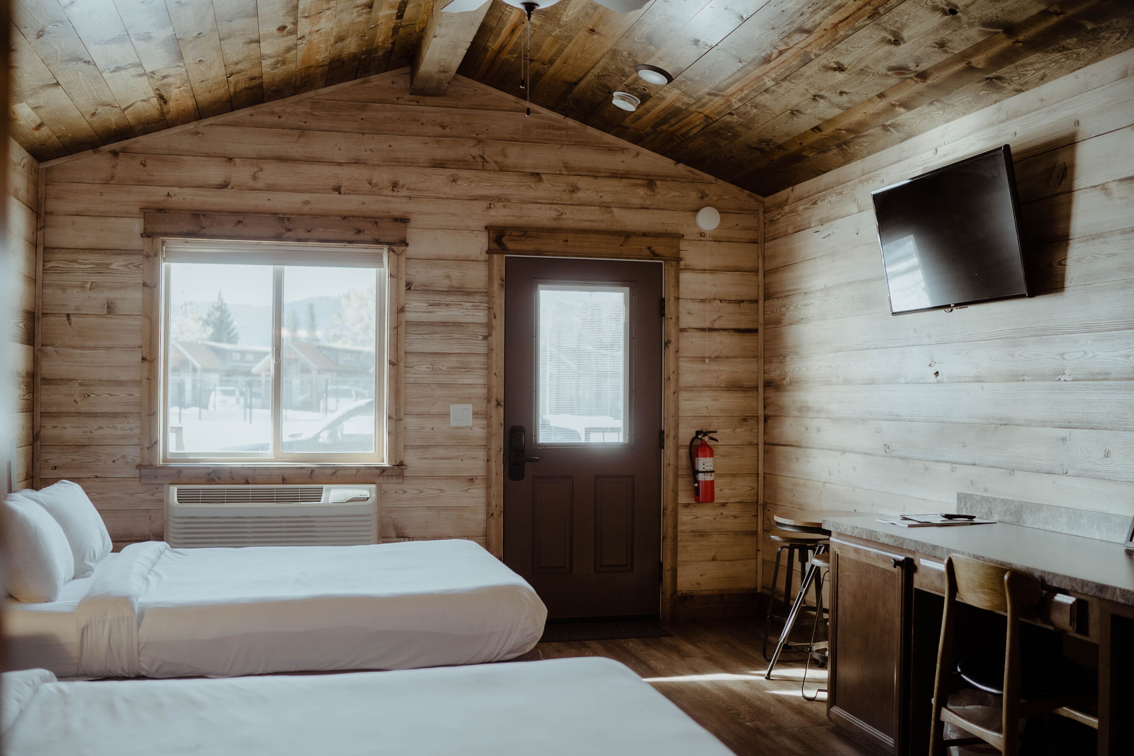 A cabin with two beds, a TV, a bar area, and a door with a window.