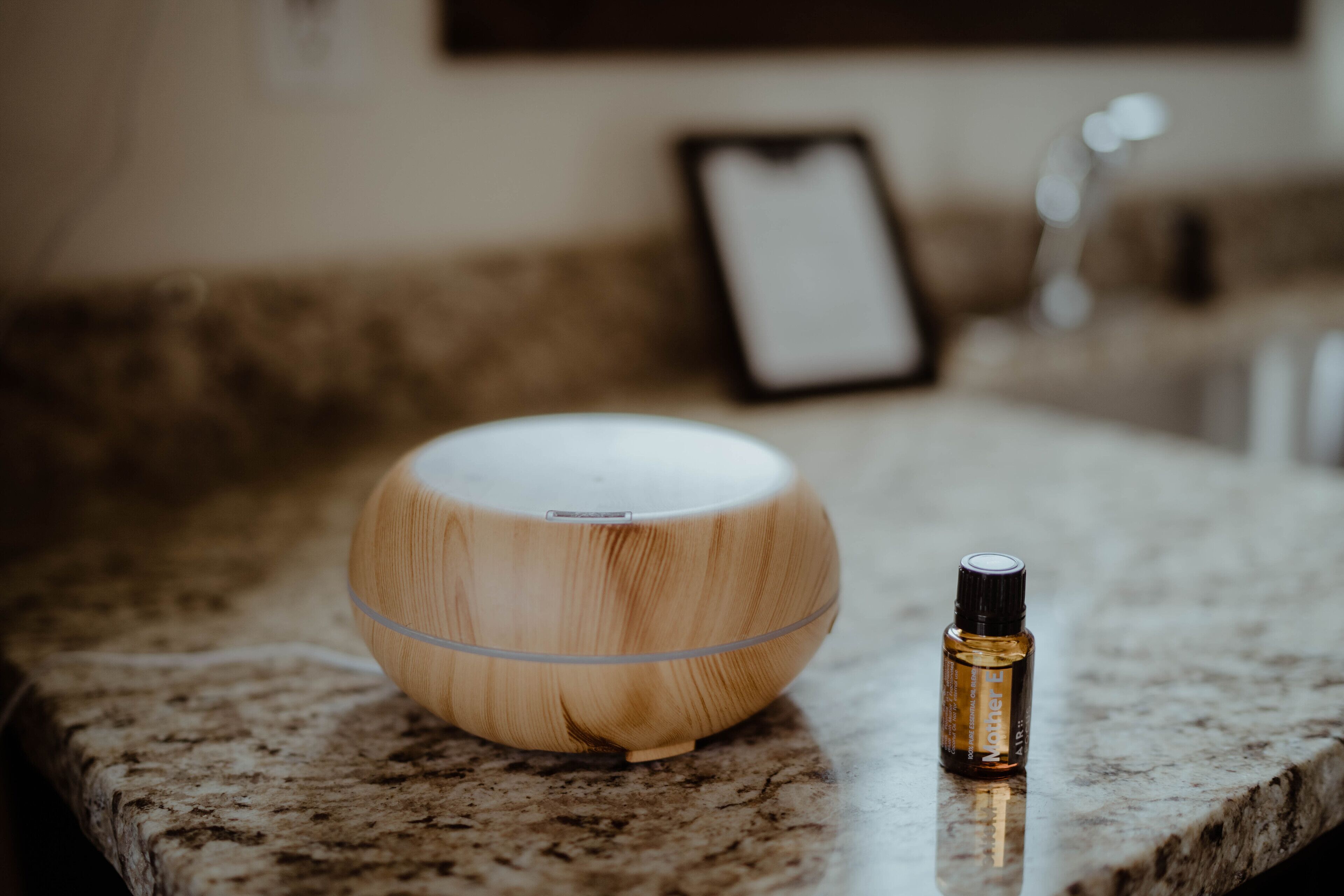 A wooden diffuser and a bottle on a granite countertop.