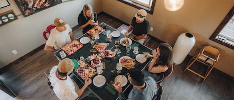 Un groupe de personnes est assis à une table, devant divers plats, des verres et un vase.