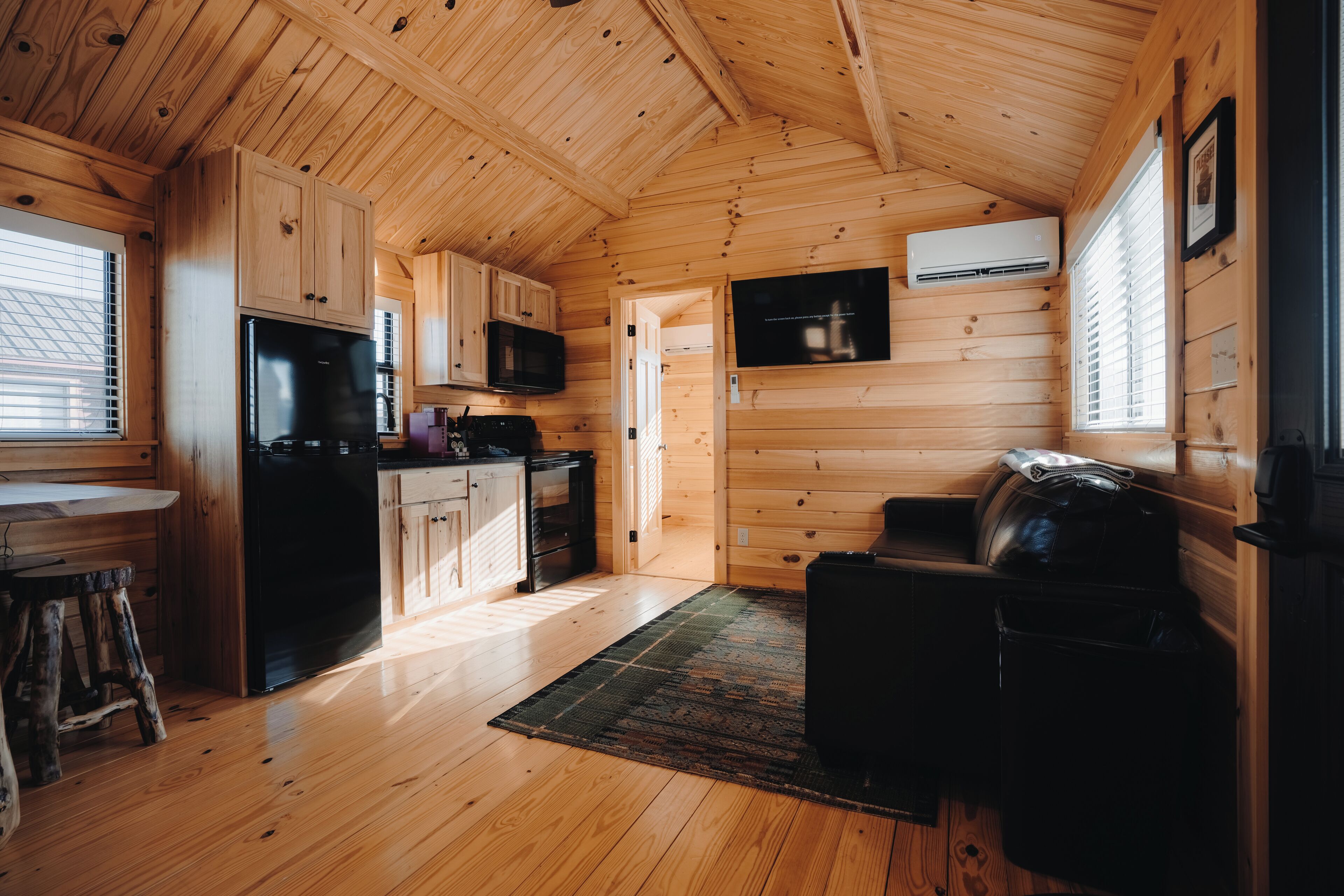 A wooden cabin interior with a kitchen, dining area, and seating space.
