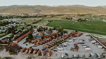 An aerial view of a residential area with multiple houses, a parking lot, and a green field.