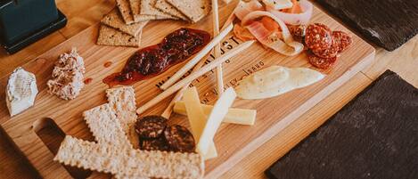 Una tabla de madera con diversos alimentos, como galletas, queso y embutidos.