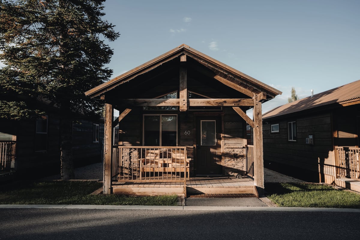 A wooden cabin with a porch, a door marked with the number 60, and a small window.
