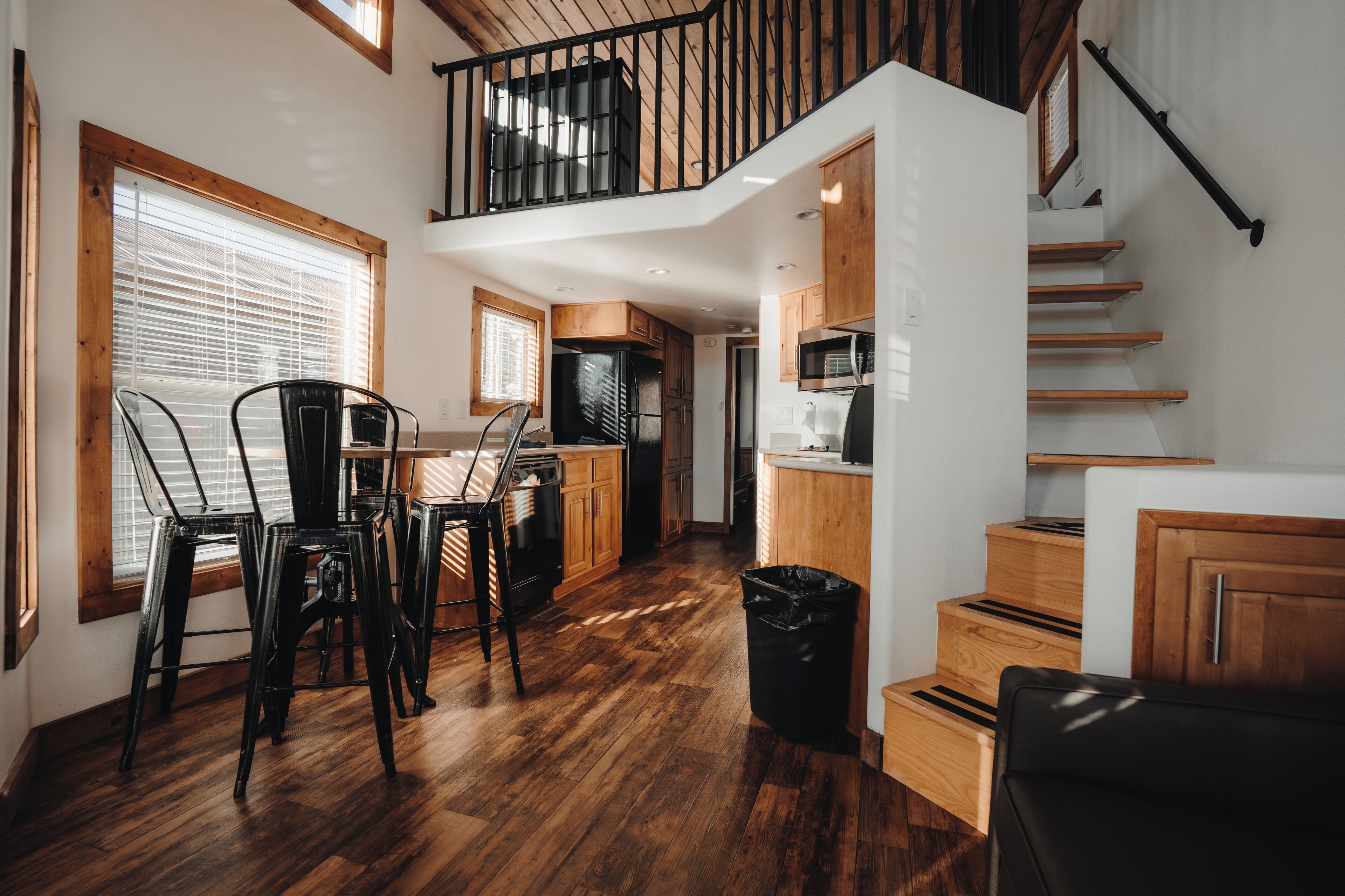 A spacious kitchen with wooden cabinets, a dining area with chairs, and a staircase leading to an upper level.