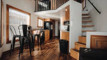 A spacious kitchen with wooden cabinets, a dining area with chairs, and a staircase leading to an upper level.