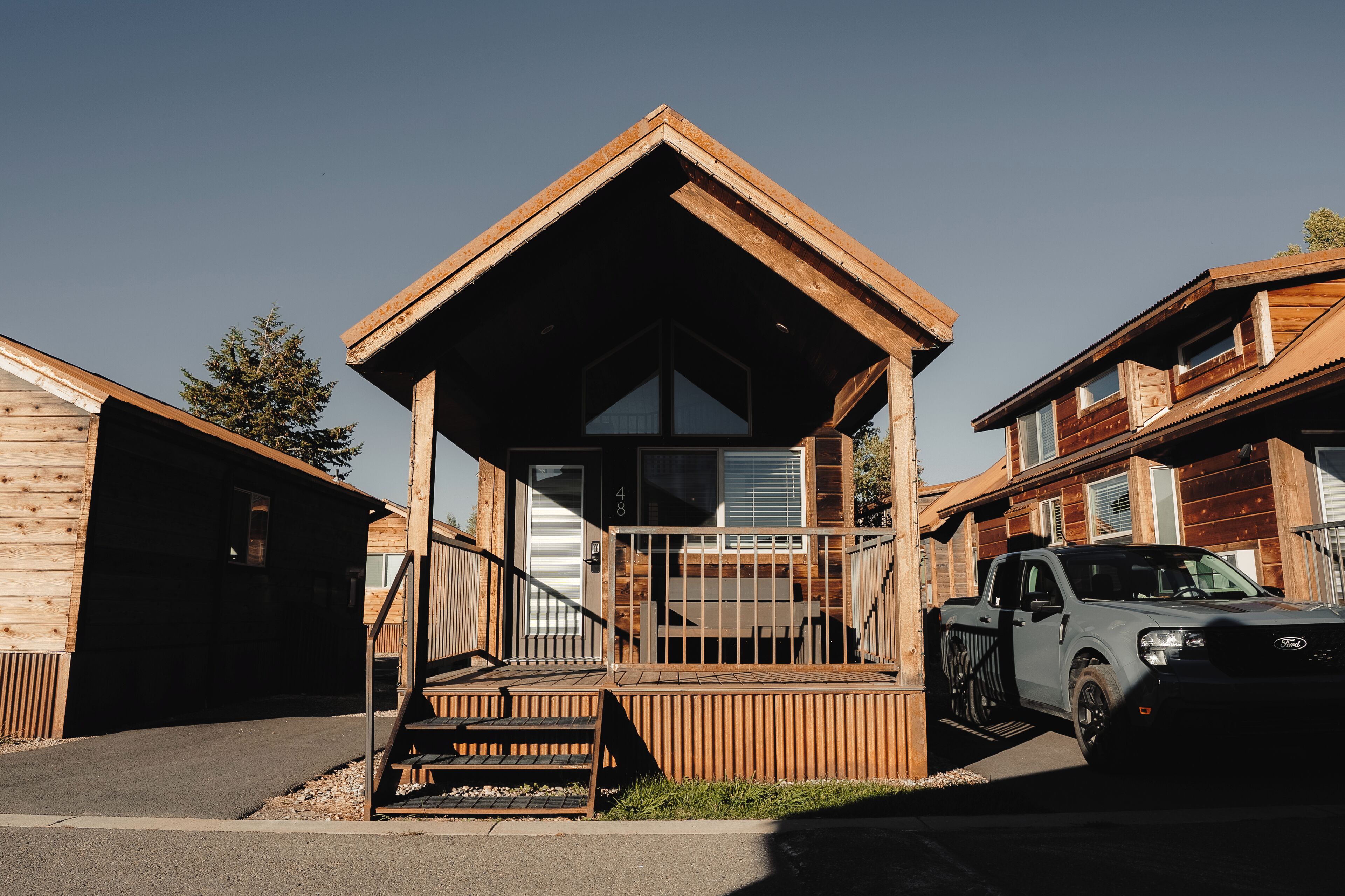 A wooden cabin with a covered porch, a garage, and a parked truck.