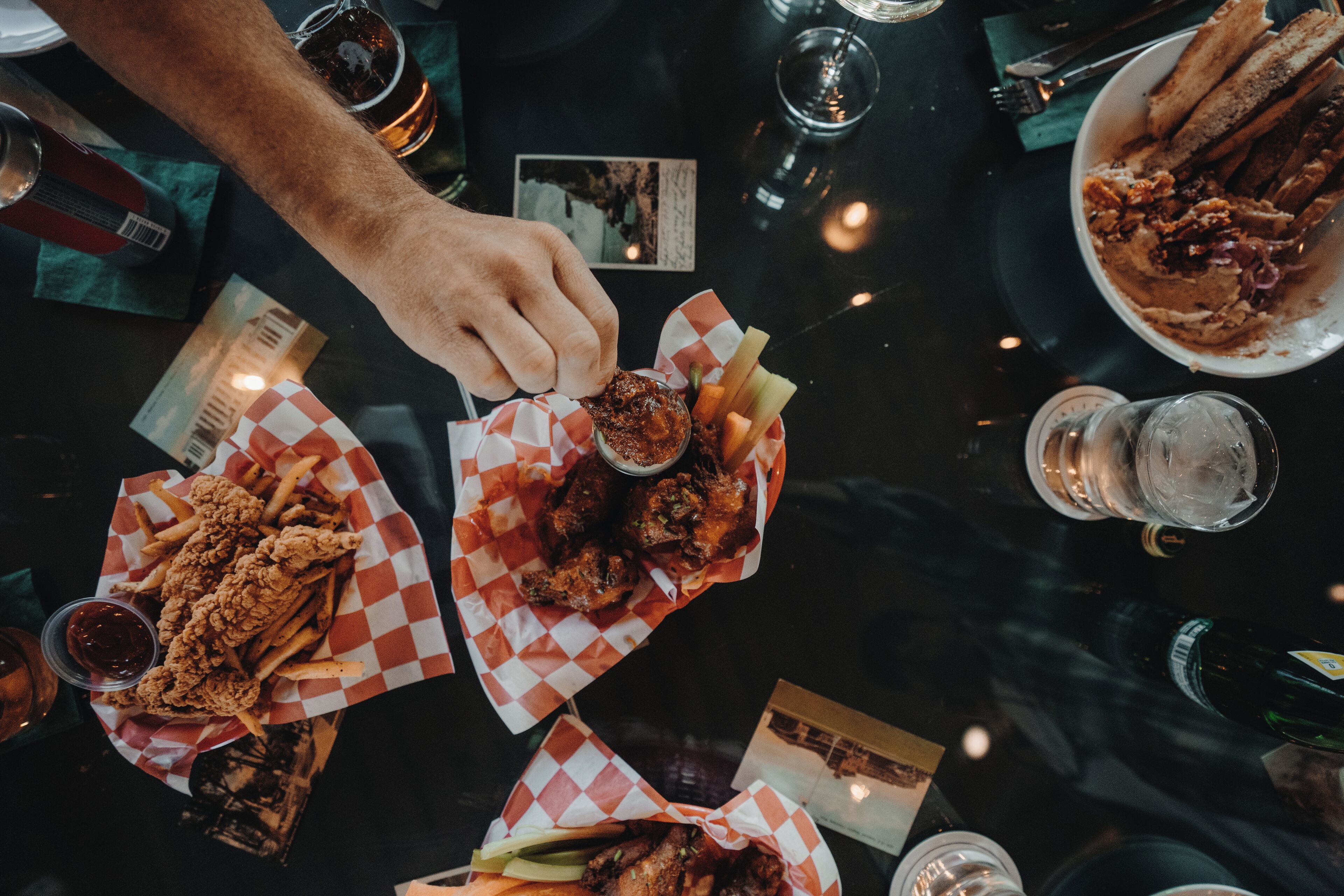 A table with various food items, including fried chicken and fries, and several glasses of beverages.