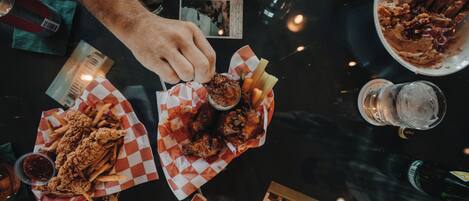 A table with various food items, including fried chicken and fries, and several glasses of beverages.