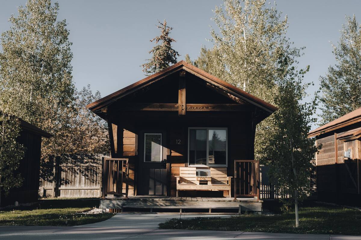 A wooden cabin with a porch, a window, and a door.