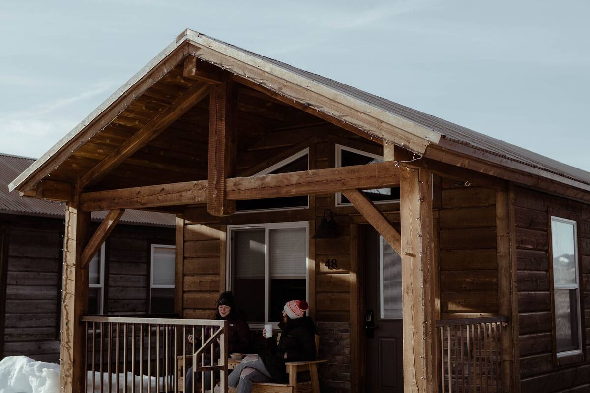 A wooden cabin with a porch and a single visible window.