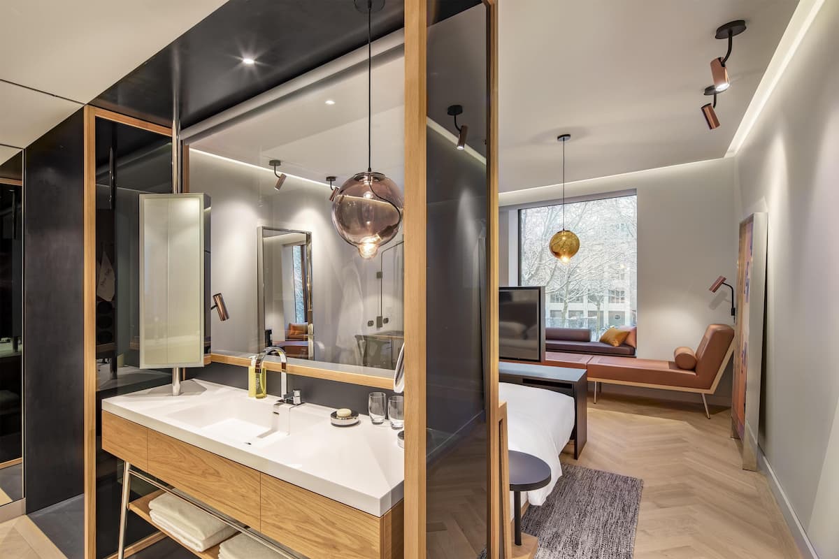 Un baño moderno con un espejo grande, tocador de madera y cabina de ducha de vidrio.