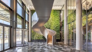 A modern interior with a spiral staircase, large windows, and a checkered floor. - ANDAZ MUNICH SCHWABINGER TOR, BY HYATT (Munich)