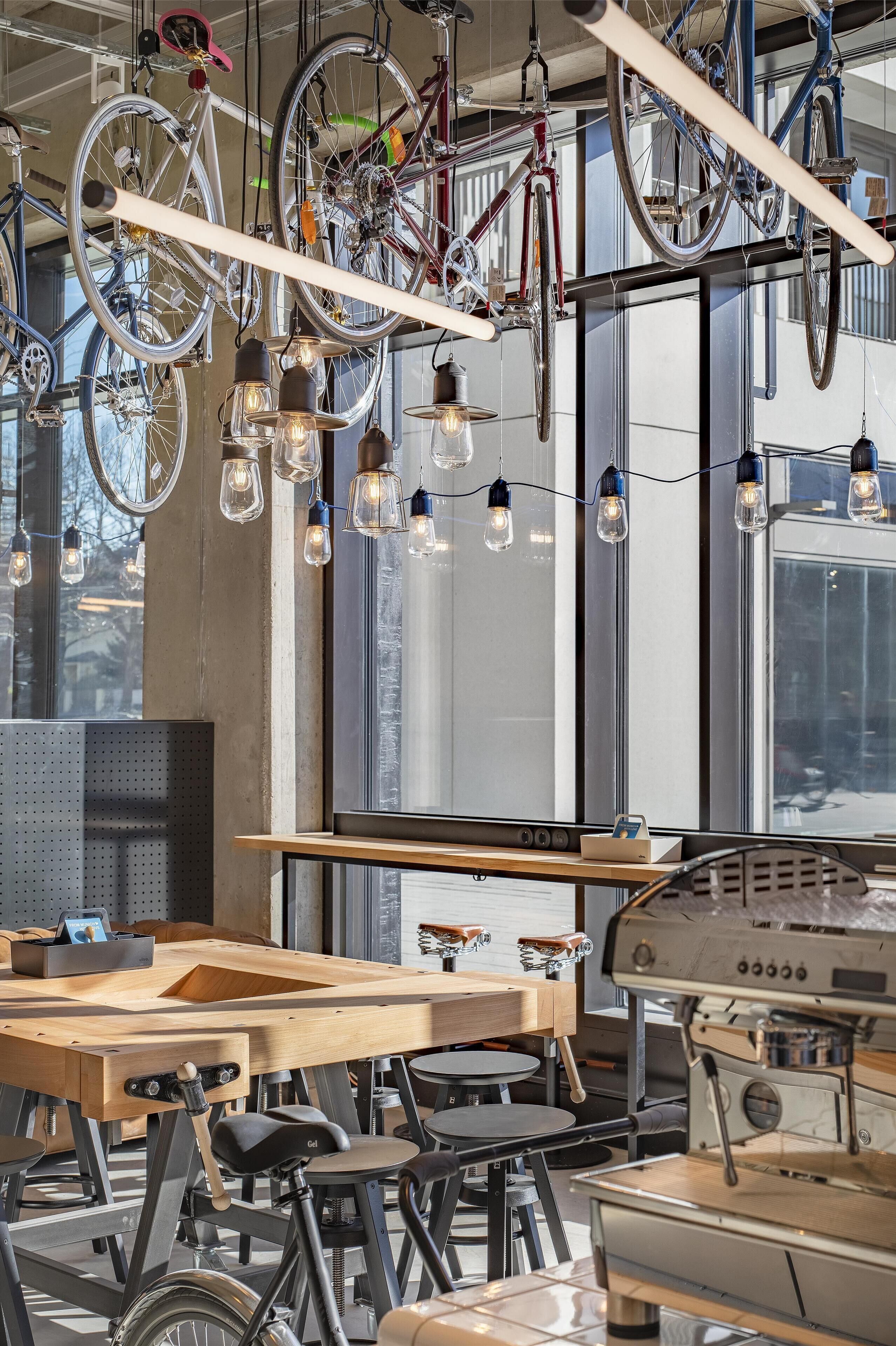 A café with bicycles hanging from the ceiling, a coffee machine, and a wooden table.