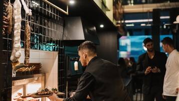 A bar area with a bartender serving drinks, a counter with various items, and a colorful wall in the background.