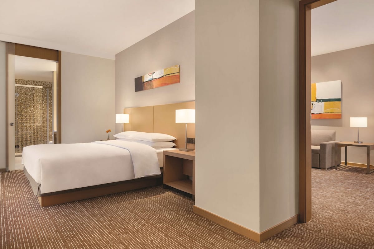 A hotel room with a large bed, two bedside tables with lamps, a wall-mounted artwork, and a carpeted floor.