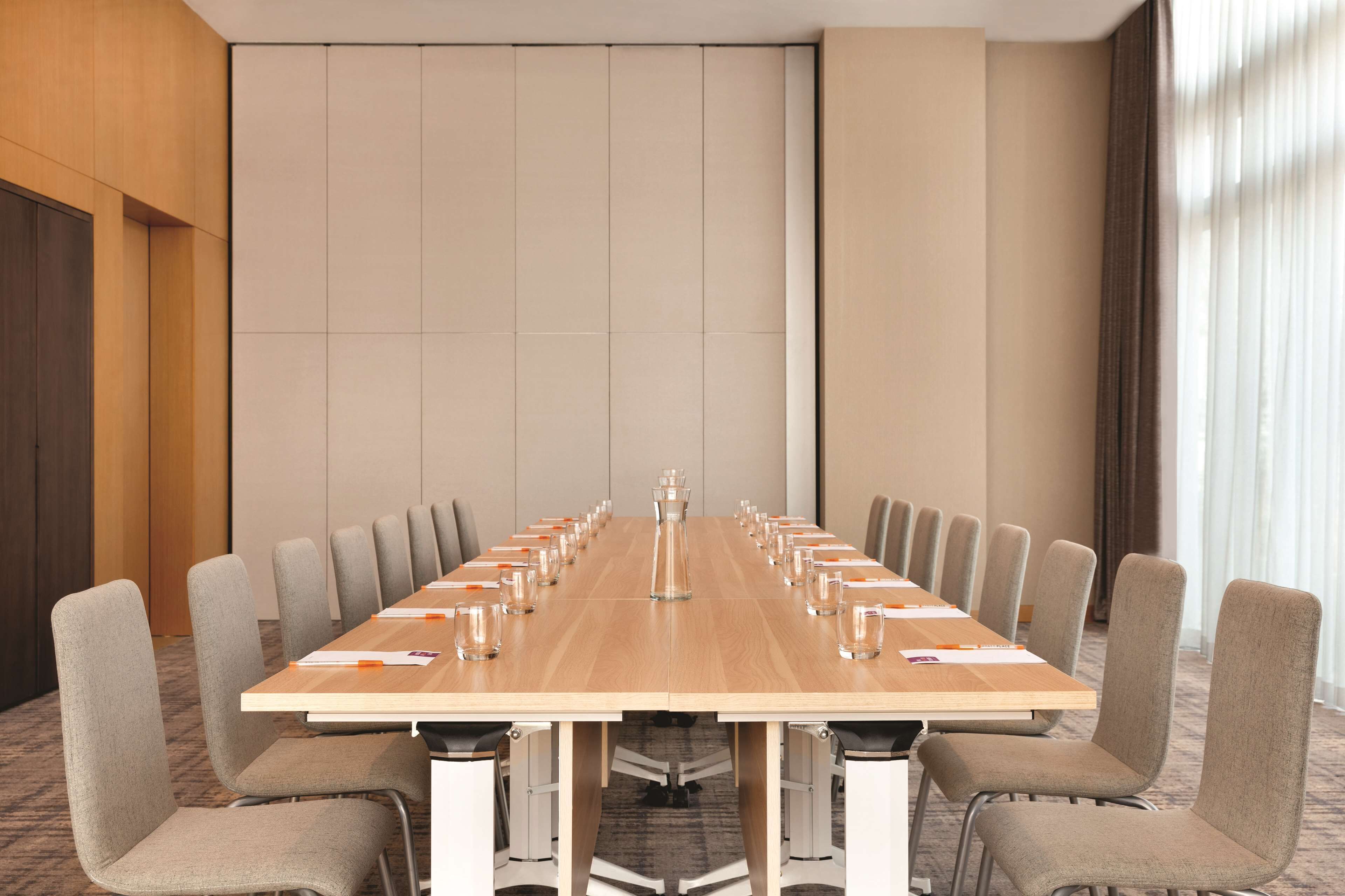 Une salle de conférence dotée d’une longue table, de nombreuses chaises et d’une décoration aux couleurs neutres.