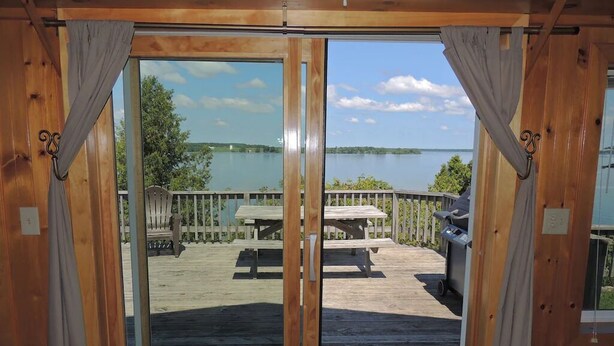 A wooden deck with a view of a lake and picnic tables.