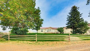 A house with a red roof, surrounded by a wooden fence, and a large tree to the left. - Ranch House in Boulder! Gateway to Nearby Parks! (Boulder)