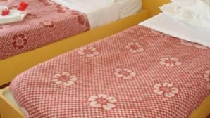 Two twin beds with floral-patterned bedding, a small table with a red item, and a yellow headboard. - Tunisian Village Hammamet (HAMMAMET NORD)