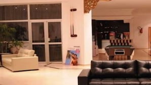 A modern hotel lobby with a black leather sofa, a white armchair, and a pool table. - Tunisian Village Hammamet (HAMMAMET NORD)