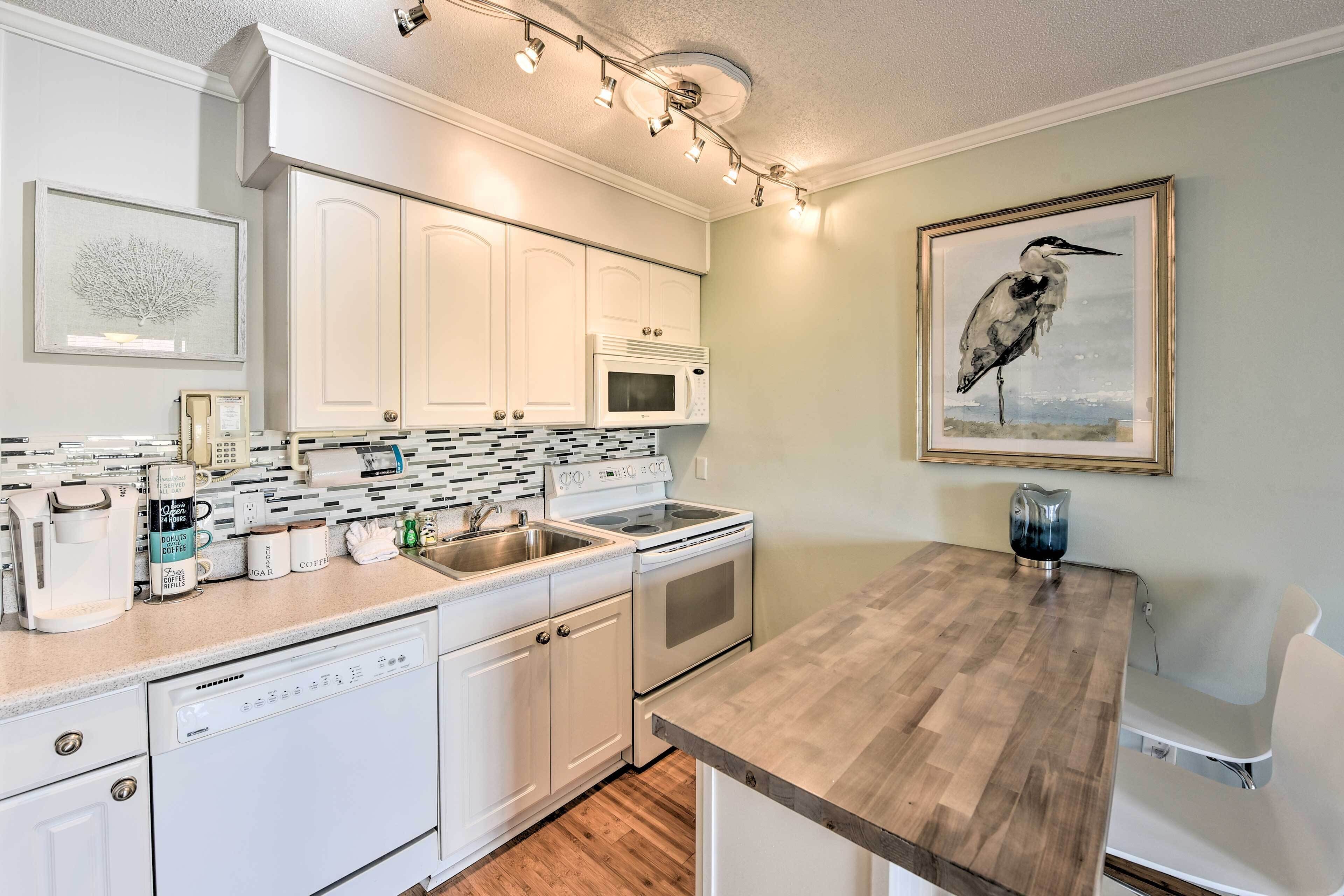 A modern kitchen with white cabinetry, a built-in microwave, a stainless steel sink, and a wooden countertop.