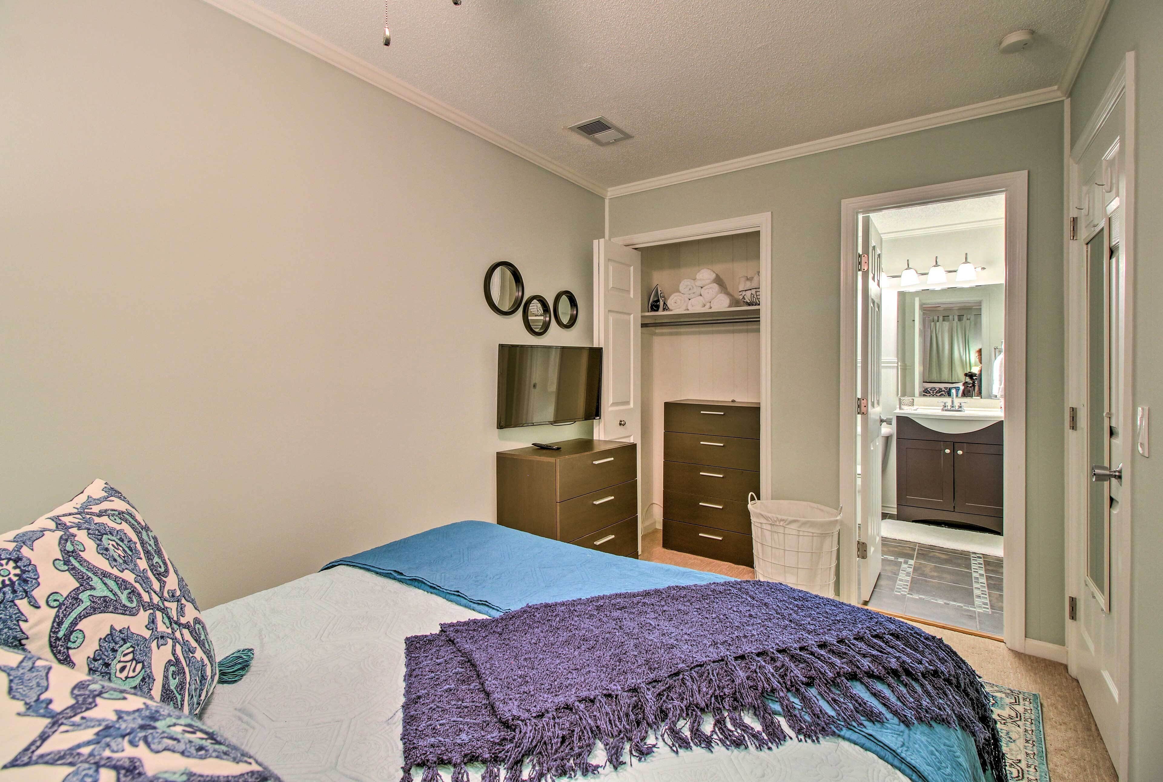 A bedroom with a bed, a dresser, a mirror, and a walk-in closet.