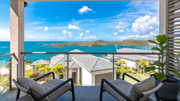 Ein Balkon mit zwei Stühlen und Blick auf das Meer, im Hintergrund ein Gebäude.