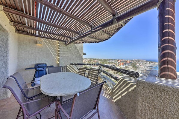 Un balcon avec une table et des chaises, un barbecue et une vue sur la ville.