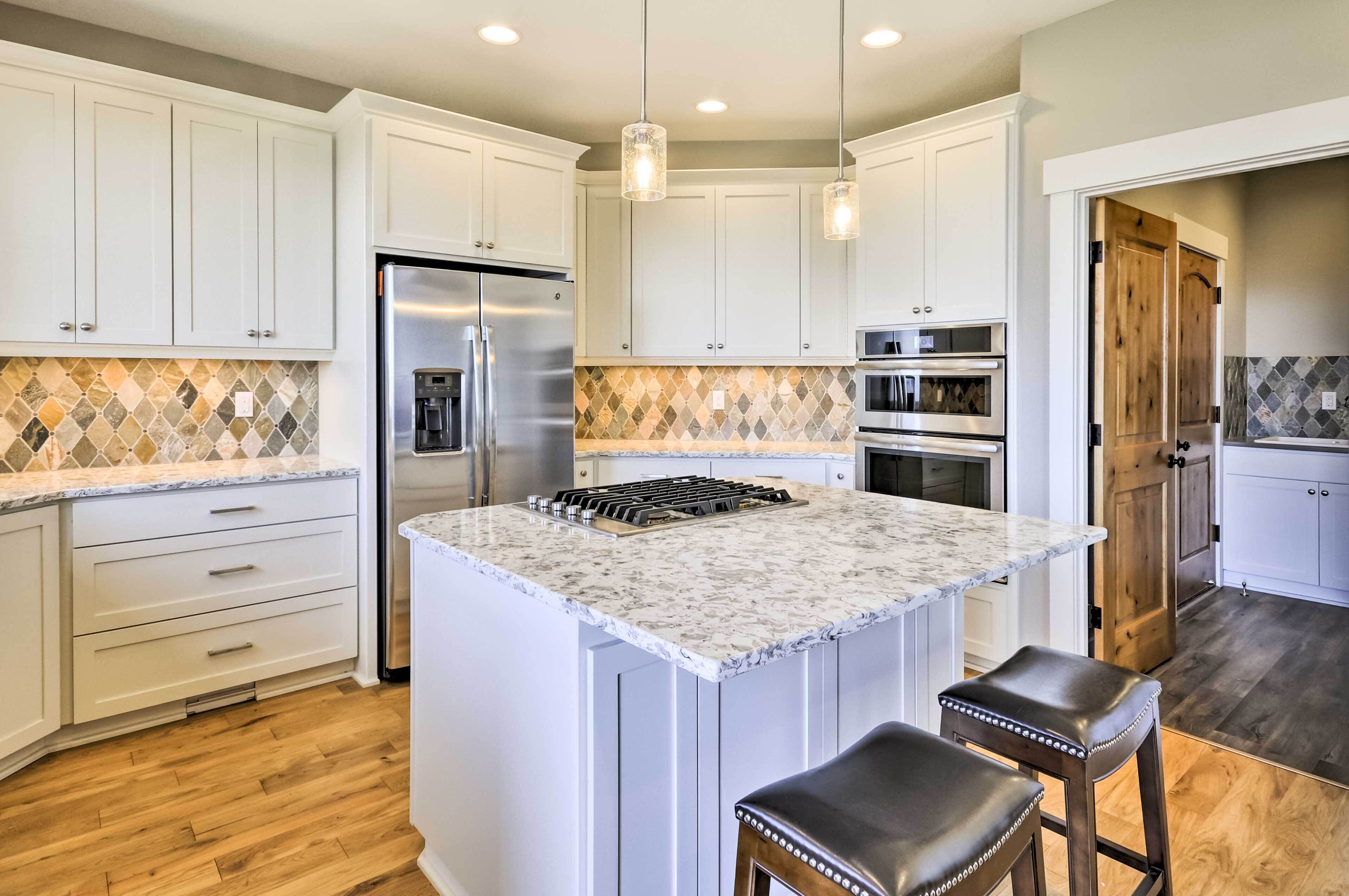 A modern kitchen with white cabinets, a central island, stainless steel appliances, and a patterned backsplash.