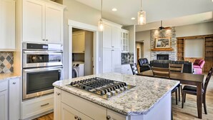 A modern kitchen with white cabinetry, a built-in oven, and a central island with a gas stove. - Chic Willamette Valley Home w/ Deck & Vineyard! (Gaston)