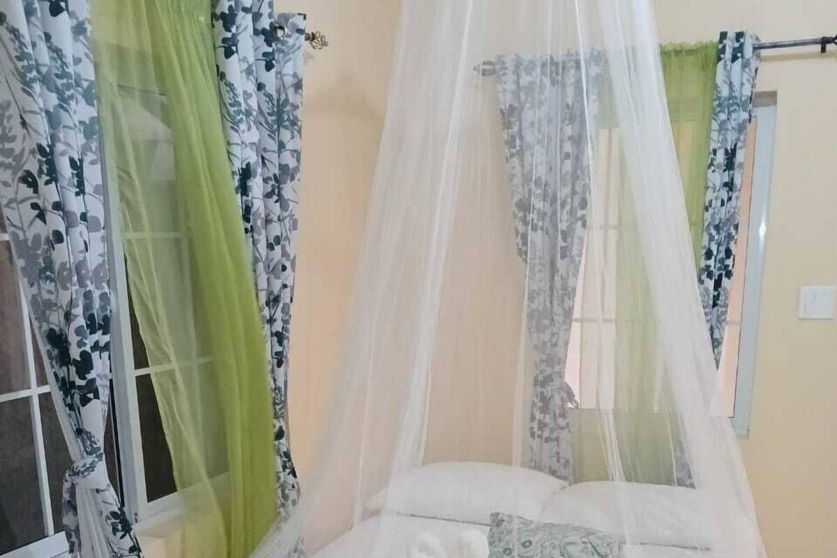 A bed with a canopy, curtains, and a window.