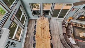 A dining area with a wooden table and chairs, a stone fireplace, and large windows. - Amazing Lake Views, Game room, Private Beach, Hot Tub, Boats and Firepit (Tobyhanna)