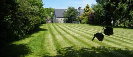 A well-maintained lawn with a stone building in the background.
