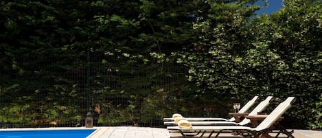 A poolside area with lounge chairs and a clear blue pool.